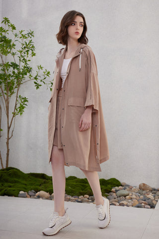 Brown hooded longline jacket with drawstring hood, worn with a top