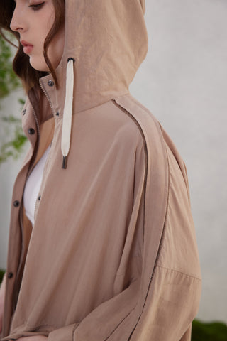 Close-up of brown hooded jacket with beaded shoulder detail and drawstring cord