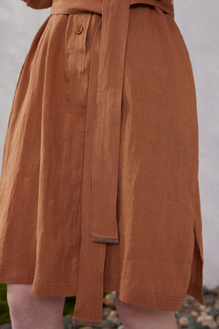 Close-up of brown linen shirt dress with button placket and tied waist