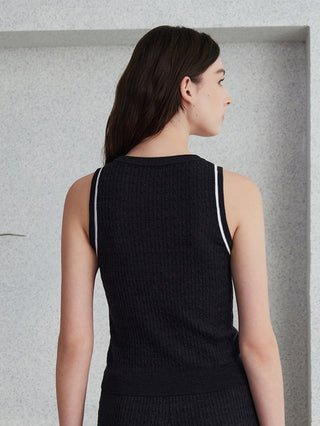 Back view of dark sleeveless knit sweater with contrast trim across shoulders