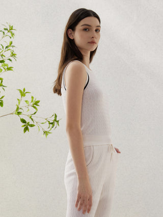 White sleeveless knit sweater with contrast trim at neckline and armholes