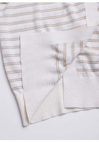 Close-up of white cardigan side pocket and hem edge, tan and blue striped fabric