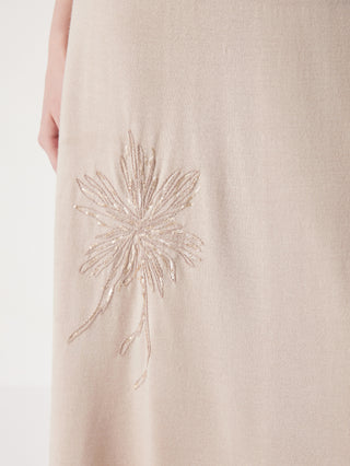 Close-up of beige skirt fabric with sparkling starburst flower embroidery