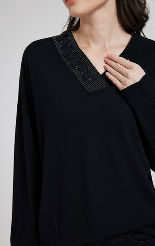 Close-up of black V-neck knit top neckline with beaded trim detail