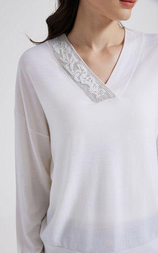 Close-up of white V-neck knit top neckline with beaded trim detail