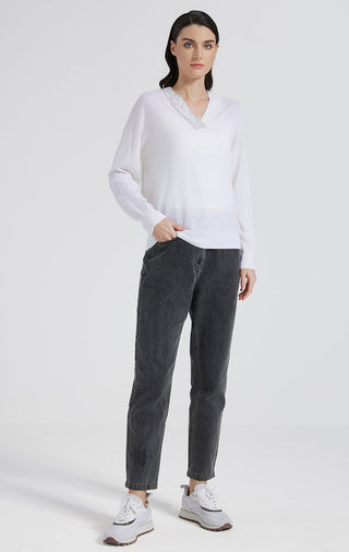 White knit top with beaded V-neck and long sleeves, paired with dark trousers