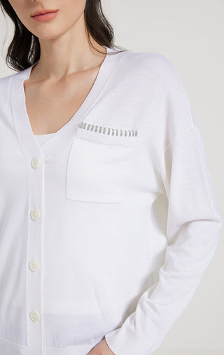 White cardigan closeup: beaded neckline trim, button placket, chest pocket