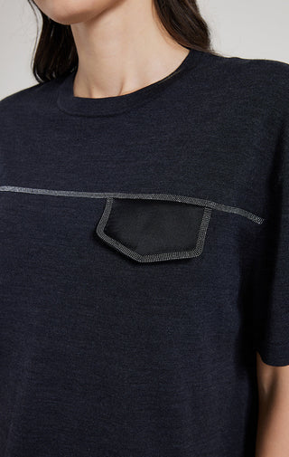 Close-up: dark top with silver thread outlined pocket graphic on chest