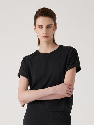 Black wool-silk knit top with crew neck and short sleeves, arms crossed