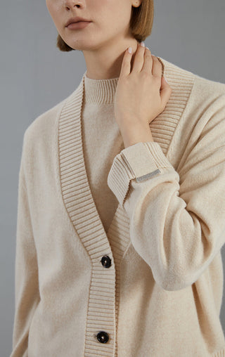 Beige cashmere cardigan close-up showing V-neck ribbing and dark button details