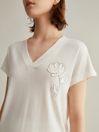 Close-up: white wool-silk knit top with V-neck and white floral embroidery near the shoulder