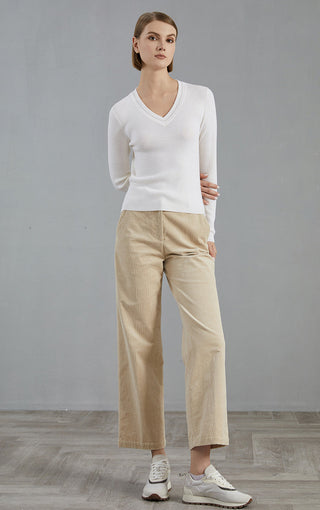 White wool V-neck ribbed knit top paired with light trousers, full-body view