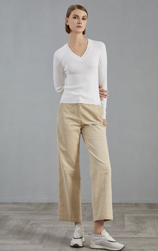 White fine wool V-neck pullover with long sleeves, worn with light-colored pants