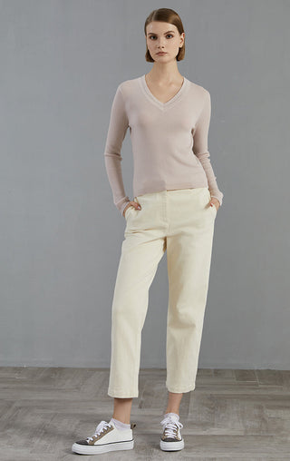 Pale taupe V-neck fine wool pullover with long sleeves, worn with light pants