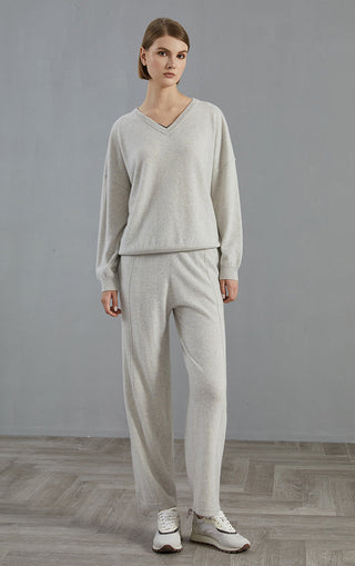 Light gray v-neck cashmere sweater worn with matching light pants, full-body view