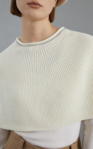 White wool knit poncho close-up of ribbed crew neckline and shoulder texture