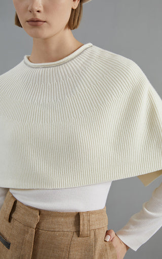 White wool poncho close-up, ribbed crew neck and textured knit across shoulders