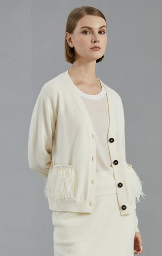 White cardigan with button front and feather-trimmed pocket edges, long sleeves