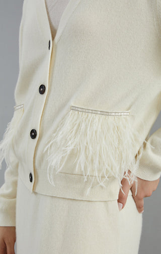Close-up of white cardigan front: black buttons and feather fringe detail