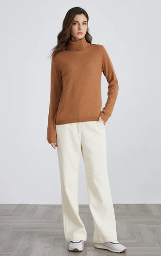 Brown cashmere blend turtleneck sweater worn with light trousers