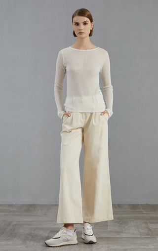 White long-sleeve ribbed knit sweater with crew neck, worn with wide-leg pants.