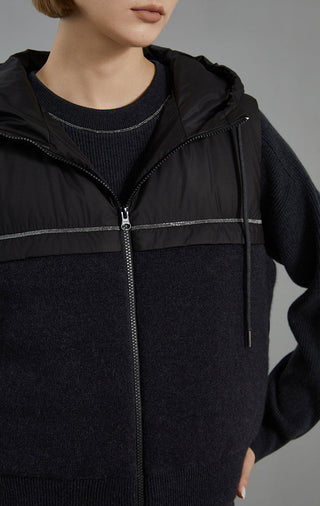 Black down vest close-up showing full zip, hood trim stripe, and knit side panel texture