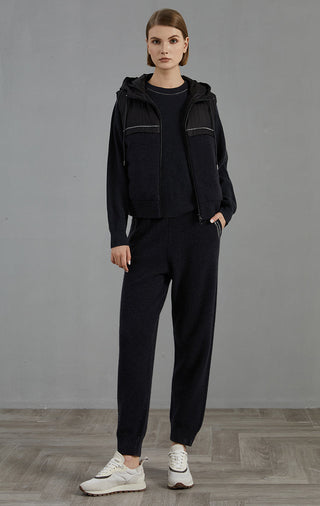 Black hooded down vest paired with black knit pants; zip-up sleeveless outer layer