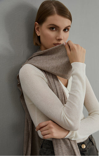 Taupe-brown wool-blend scarf worn cross-body, soft drape with frayed fringe ends