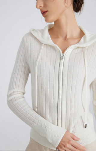 White ribbed zip hooded cardigan close-up, visible zipper pull and textured knit rows.