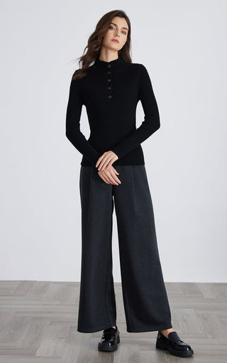 Black cashmere-blend mock neck sweater with button placket, worn with wide-leg pants