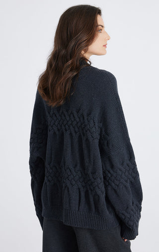 Dark blue cable-knit cardigan from back/side view with textured yoke and ribbed hem