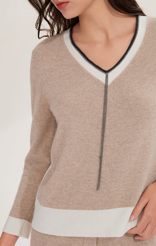 Close-up of camel cashmere knit V-neck top with black-and-white trim and shimmer chain