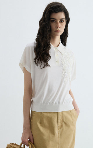White polo knit top with button placket and ornate sequin panel on the chest