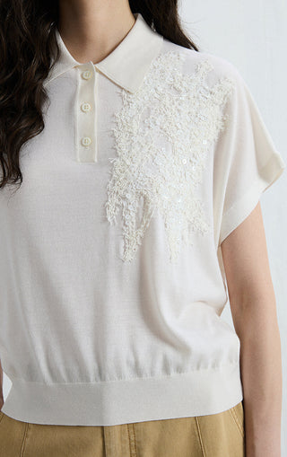 White polo knit top close-up: button placket and shimmering sequin front panel