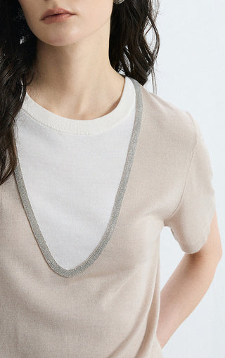 Beige knit tee close-up: contrast V-neck trim and white inner crew neckline