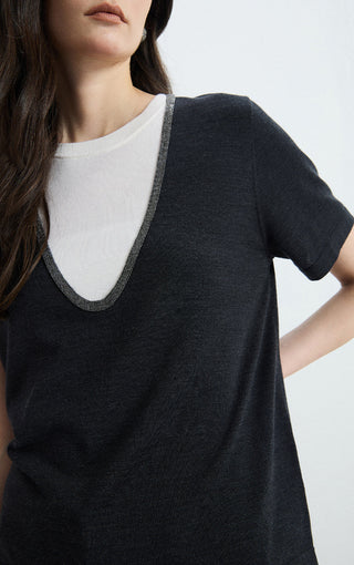 Black knit tee close-up: contrast V-neck trim over white inner crew neckline
