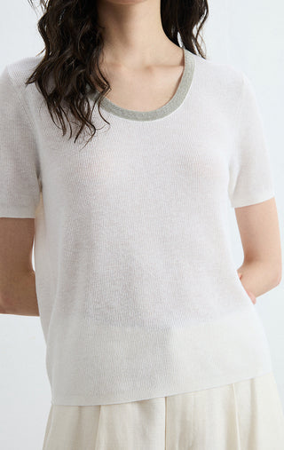 Close-up of ivory knit top chest with silver-trim crew neck