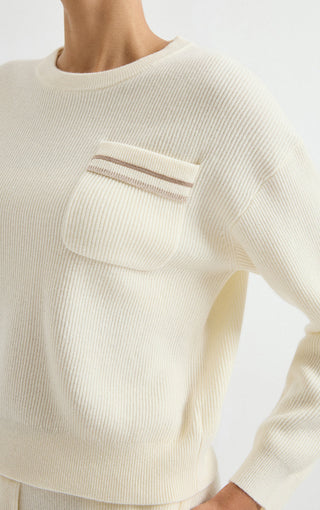 Ivory wool ribbed sweater close-up of chest pocket with beige-and-red striped trim
