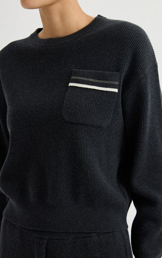 Black wool ribbed sweater close-up: chest pocket with white-and-silver striped trim