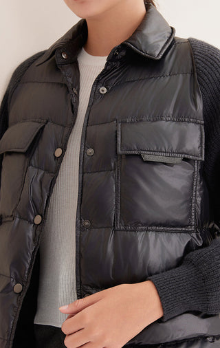 Close-up of black down shirt jacket: stand collar, snap buttons, and chest pocket