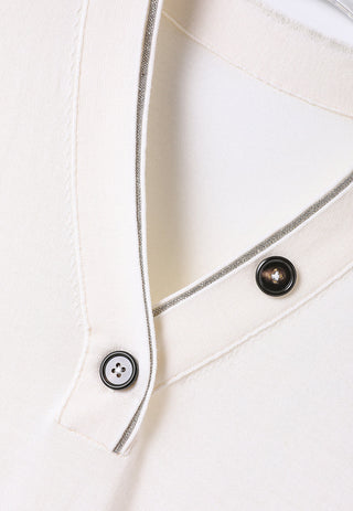 Neckline close-up: off-white placket with two buttons and shimmering trim edge
