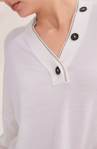 Close-up of off-white V-neck placket with two dark buttons and shimmering trim