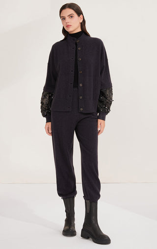 Black knit cardigan and matching dark trousers set with embellished sleeve cuffs.