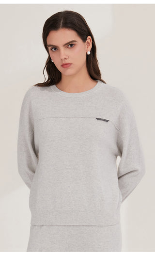 Light gray cashmere knit top with chest shimmer accent tab, crew neckline, long sleeves.