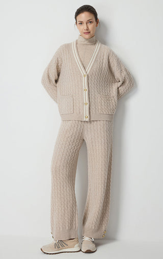 Camel wool cable-knit pants worn with relaxed fit and ribbed cuffs; side slits.