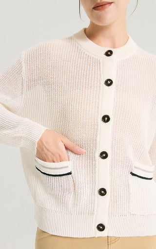 Ivory-white knit cardigan close-up with dark buttons and contrast-trimmed pockets