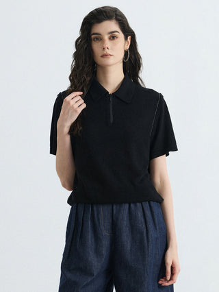 Black half-zip polo knit top with fold-over collar and vertical zip placket