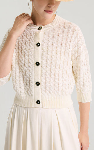 Ivory white knit short cardigan close-up showing dark buttons and cable pattern