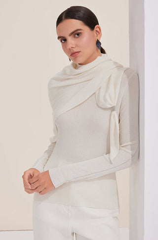 White turtleneck knit sweater worn with long sleeves; draped high collar and rib texture