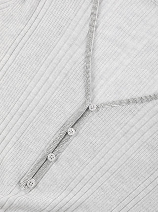 Close-up: white v-neck knit with beaded button placket along the center front